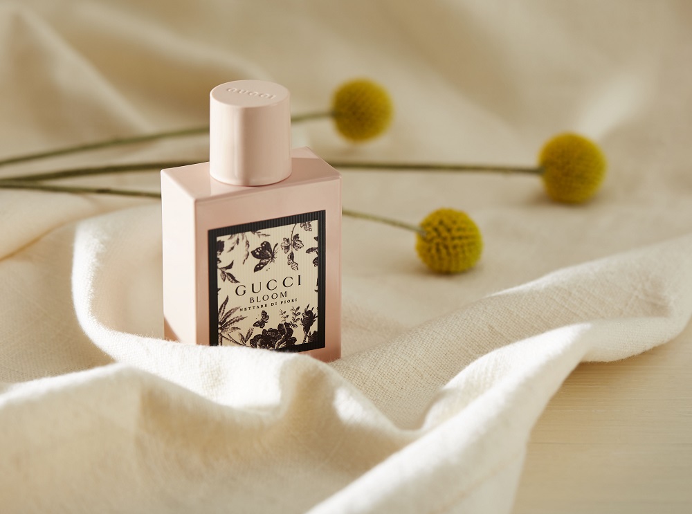 Photo du parfum Gucci Bloom avec des fleurs et du tissu de soie.