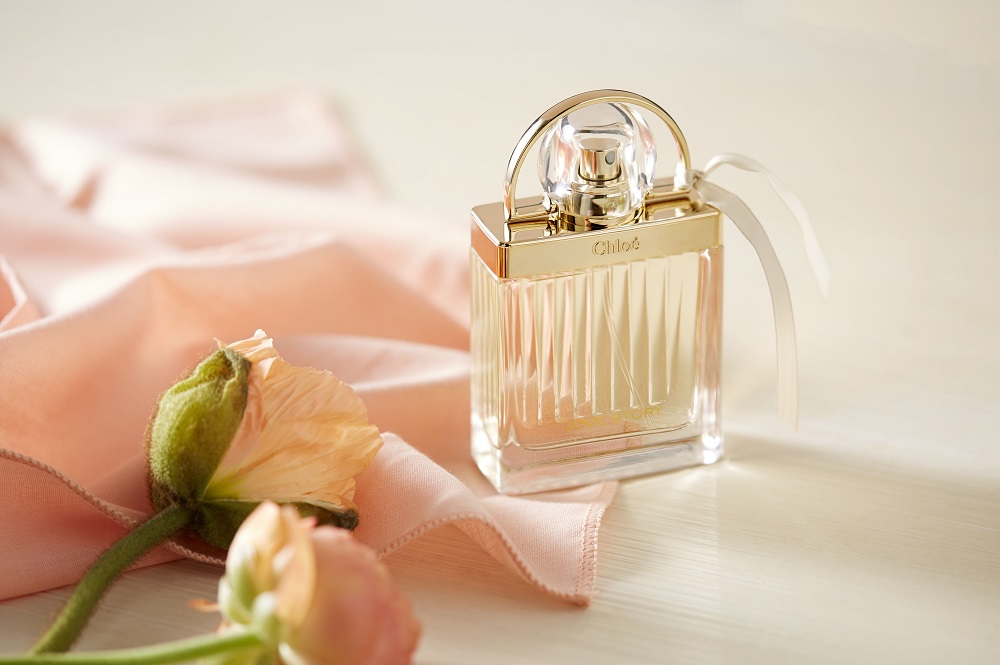 Photo du parfum Chloé Love Story avec des roses et un tissu de soie rose.