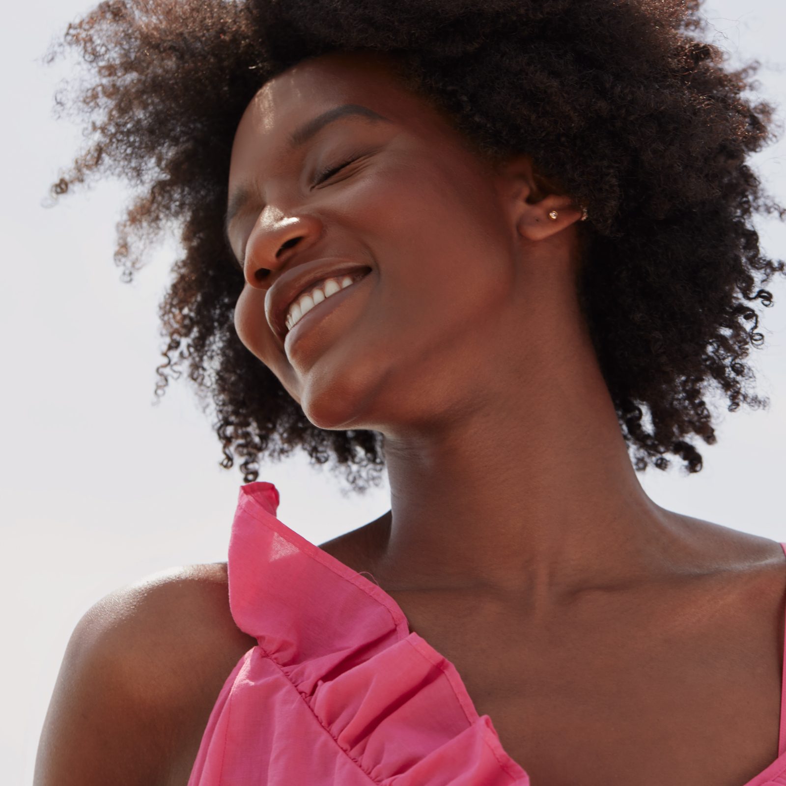 female smiling with her eyes closed in the sun