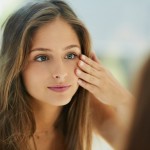 Woman looking in the mirror touching her skin