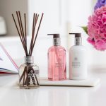 Verschiedene Produkte von Molton Brown mit Blumen auf einen Tisch platziert