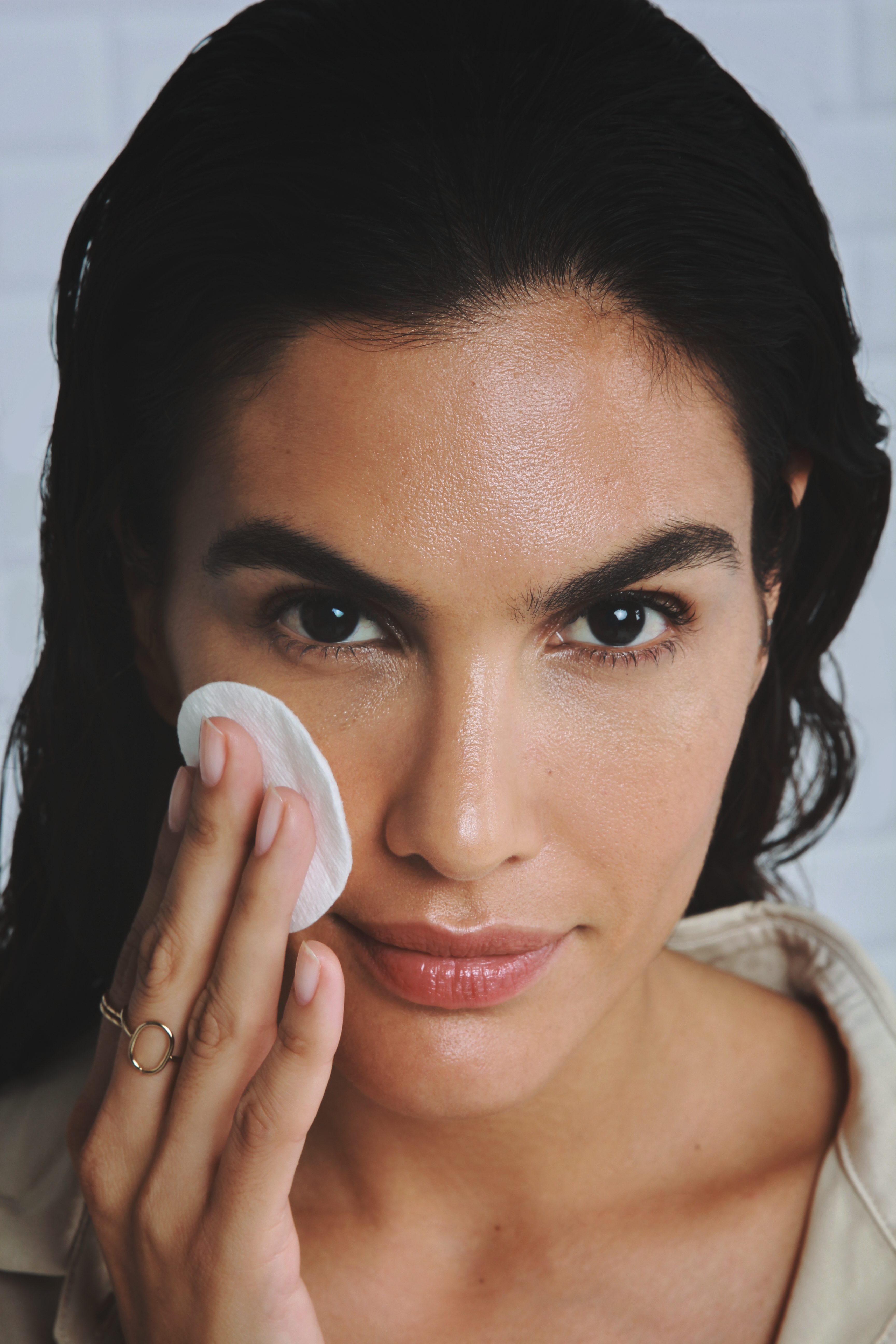 female model applying product to face with cotton pad