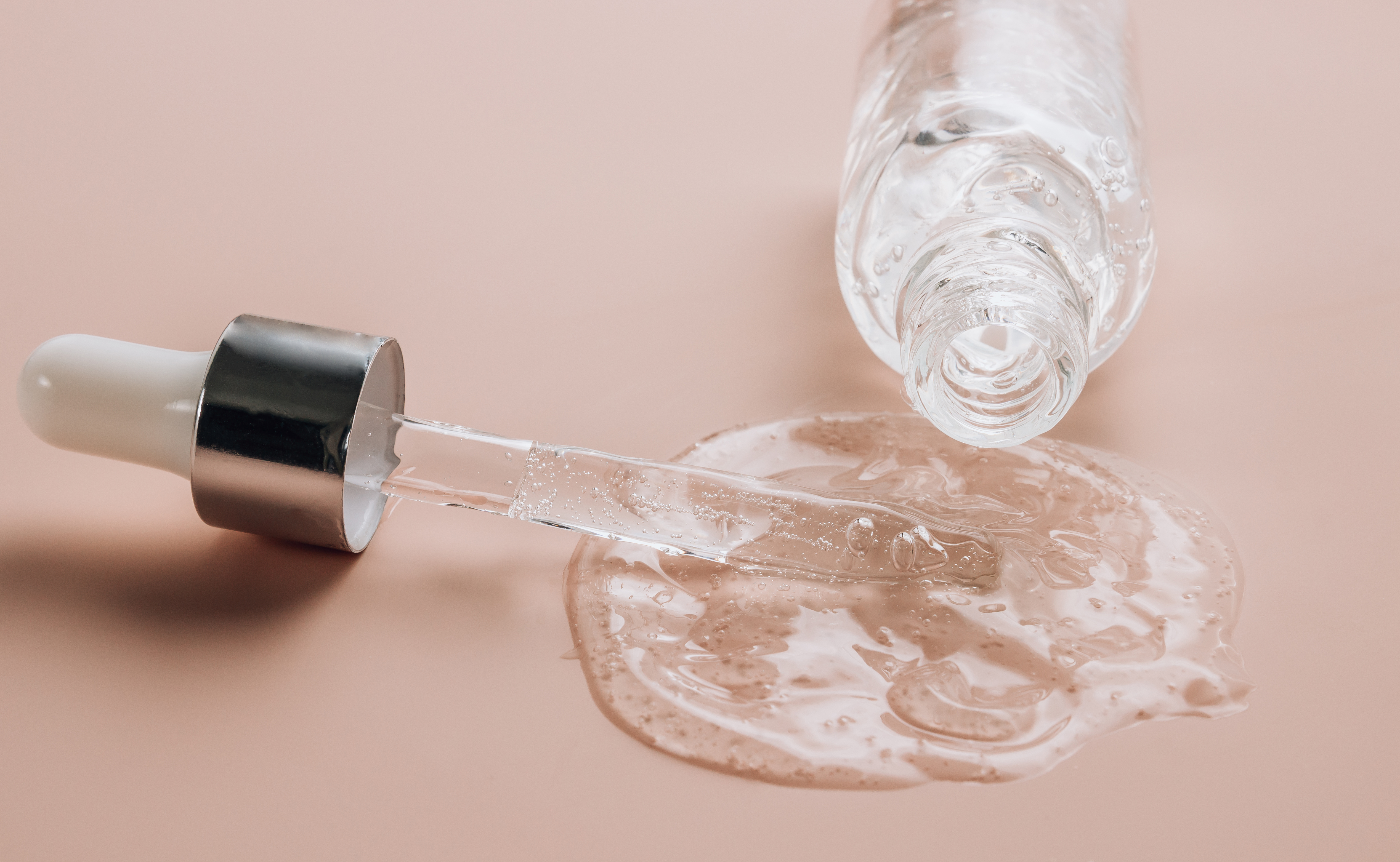 Hyaluronic acid on skin color background with oxygen bubbles. Bottle of hyaluronic acid on skin color background with oxygen bubbles. Selective focus