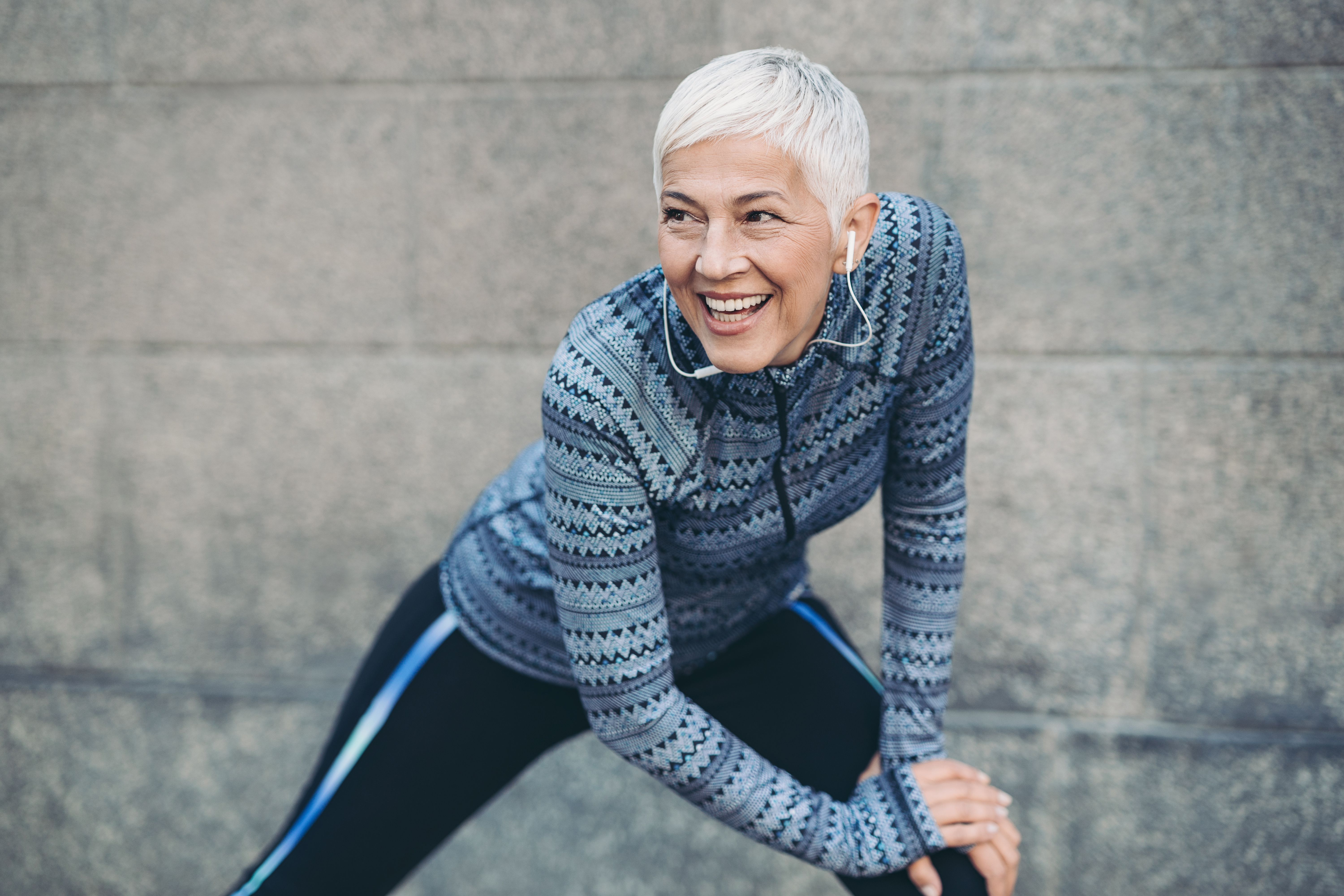 Mature woman in sports clothing stretching outside Senior female athlete exercising outdoors