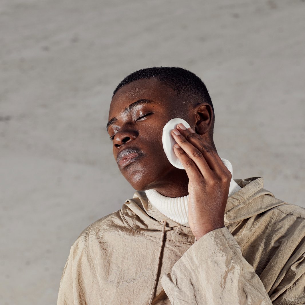 Male model applying product to face with cotton pad