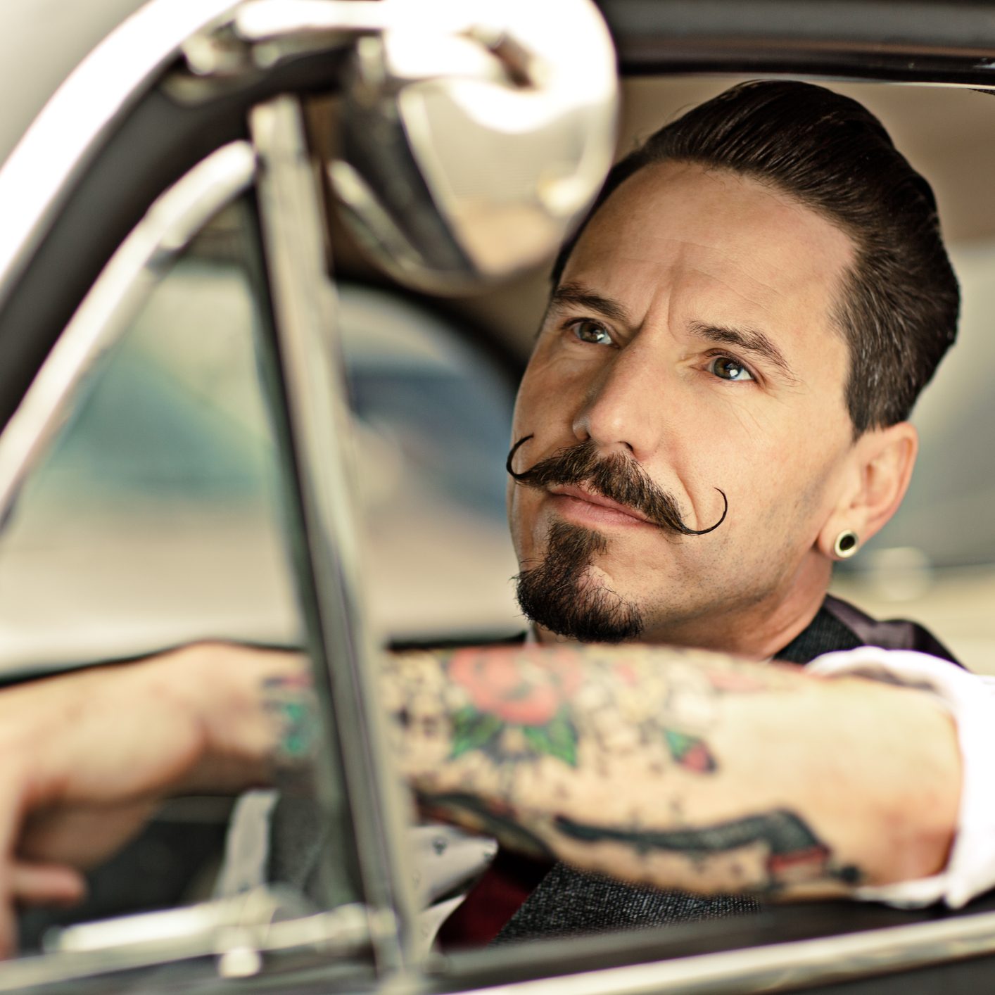 Man with moustaches sitting  in car