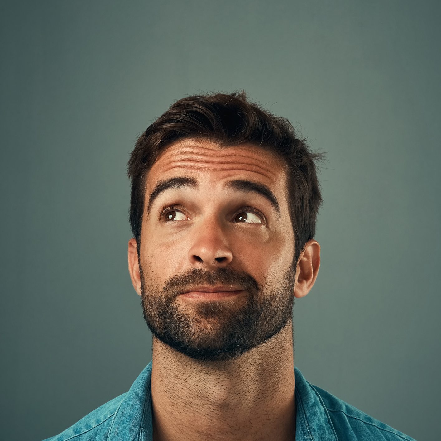 Studio shot of a handsome young man looking up against a grey background