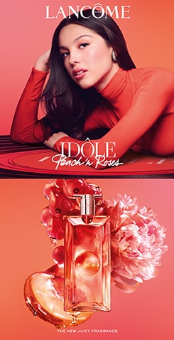 Lancôme Idôle Peach’n Roses parfum avec flacon rose devant fond rouge et fleurs roses, nouvelle fragrance. 