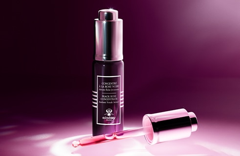 Concentré à la Rose Noire Serum von Sisley mit Pipette, präsentiert vor einem eleganten roséfarbenen Hintergrund.